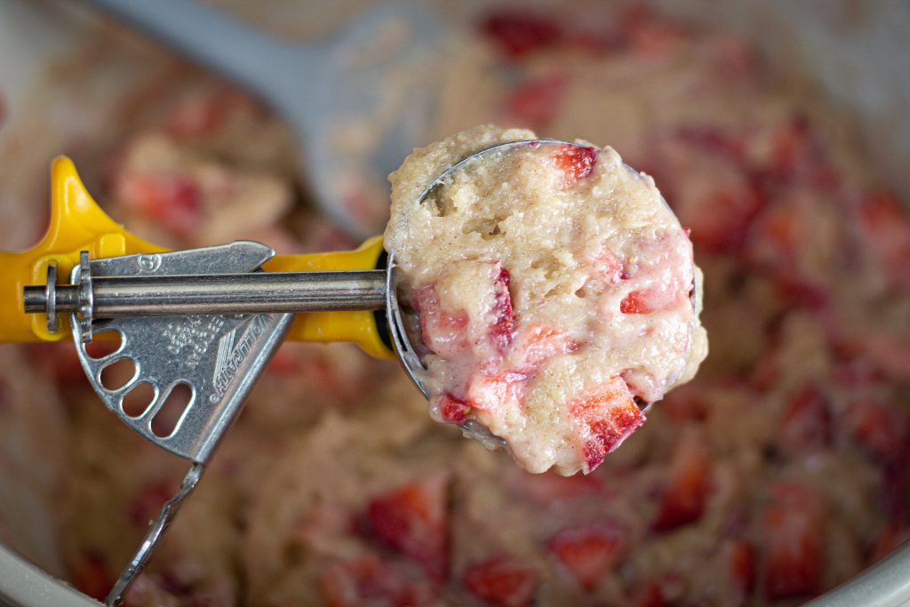 Yellow ice cream scoop filled with strawberry muffin batter